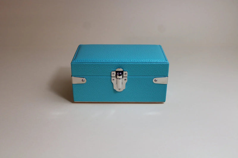 Blue textured leather box with silver clasp on neutral background