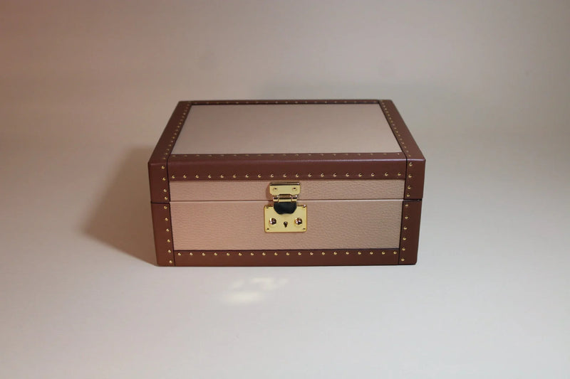 Handcrafted brown and beige leather box with gold stud accents and metal clasp on neutral background