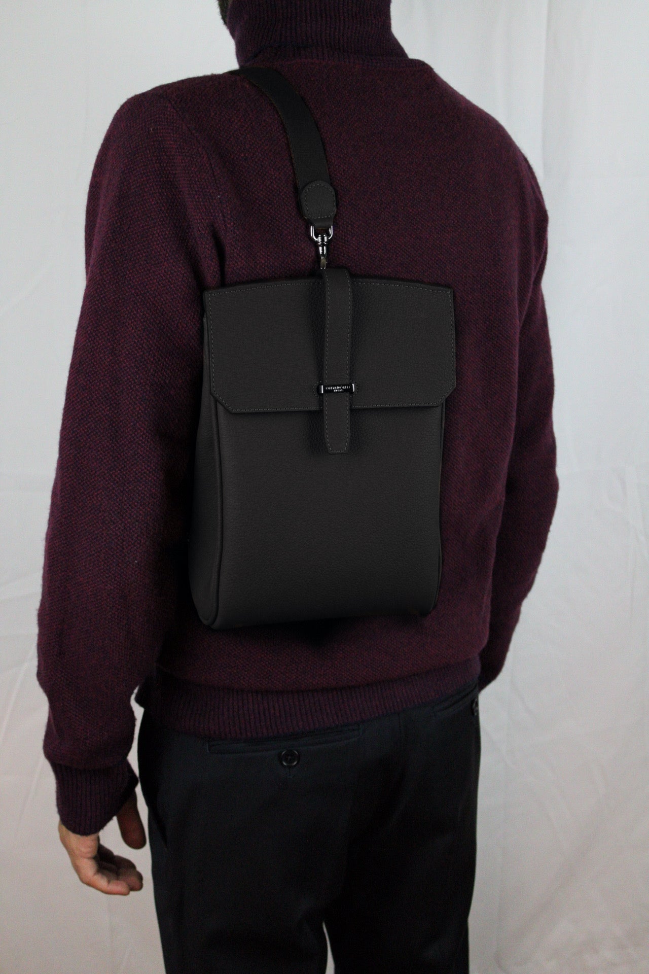 Person wearing a black backpack on a plain background