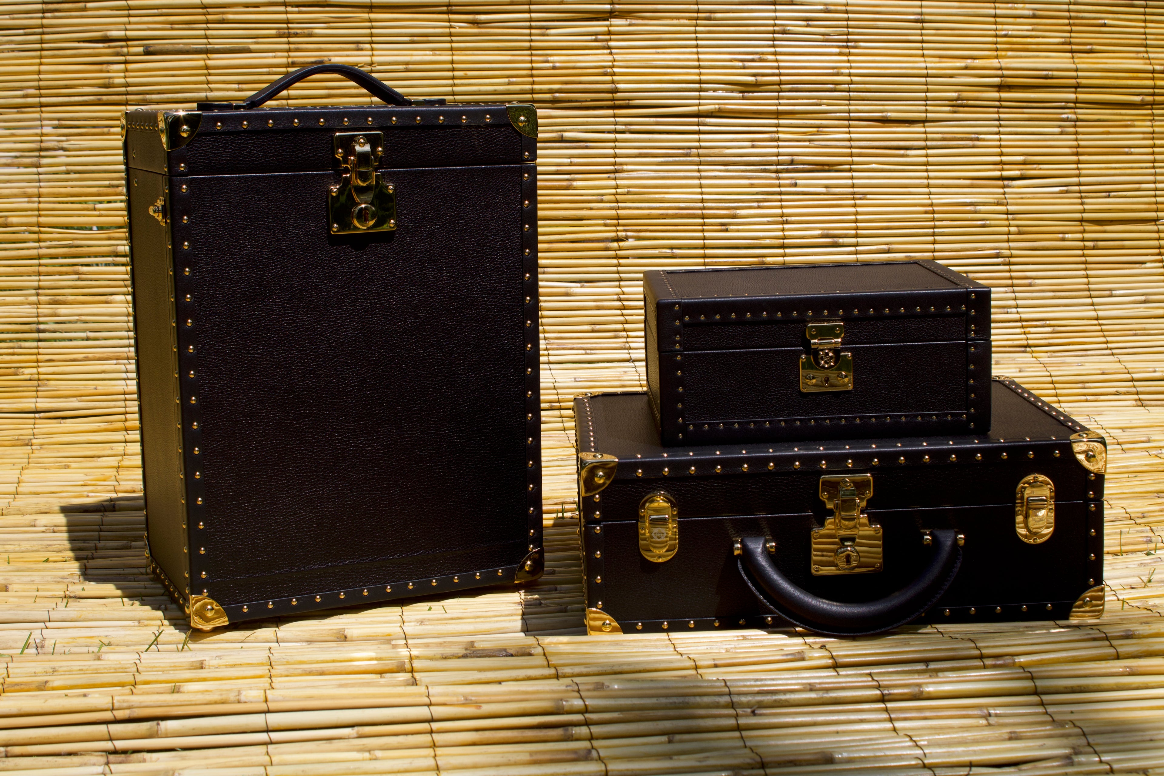 Set of black suitcases with gold accents on a bamboo background